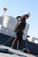 איטום באמצעות הנחת גלילי יריעות ביטומניות על גג דירה בנשר