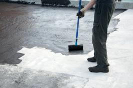 ביצוע איטום גג באמצעות מריחת חומר משחתי עם מברשת רולר על גג דירה במכבים