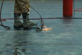 התקנת של יריעות איטום באמצעות מבער במהלך עבודת איטום בלוד