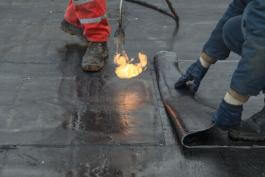 קבלני איטום מניחים יריעות על גבי איטום ישן בגג דירה בבית שאן