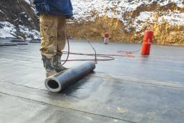 פועל בניין מבצע איטום עם יריעות של בסיס מבנה חדש ביקנעם